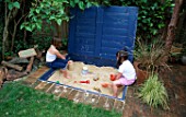 HARRIET AND NANCY MATTHEWS PLAY IN THE SANDPIT DESIGNED BY CLARE MATTHEWS.