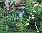 CAROLYN HUBBLES SHROPSHIRE GARDEN. BRONZE STATUE WITH ENGLISH ROSE REDOUTE  ROSA MAGENTA AND ROSA CHARLOTTE