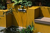 WATER FEATURE: POST BOX STYLE FOUNTAIN WITH YELLOW RENDERED WALLS  AND HOSTAS IN BACK GROUND.  DESIGNER JOE SWIFT.