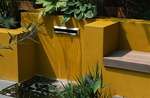 WATER_FEATURE_POST_BOX_STYLE_FOUNTAIN_WITH_YELLOW_RENDERED_WALLS__AND_HOSTAS_IN_BACK_GROUND__DESIGNE