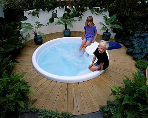 HAZEL_AND_ROBERT_PLAY_IN_THE_SPA_POOL_SURROUNDED_BY_PALMS_IN_POTS_AND_DECKING_HAMPTON_COURT_2000__DE