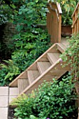 WOODEN STEPS LEAD FROM PAVED AREA ONTO DECKED TERRACE IN A GARDEN DESIGNED BY SARAH LAYTON