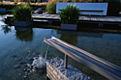 GALVANISED METAL SHUTE FORMS WATER SPOUT IN MINIMALIST WATER GARDEN DESIGNED BY ULF NORDFJELL. FOLIAGE OF IRIS ENSATA IN GALVANISED CONTAINERS.  HEDENS LUSTGARD  SWEDEN