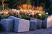ANGULAR ROCKS SURROUND MINIMALIST GARDEN BY ULF NORDFJELL. PLANTING WITH LILUM REGALE AND DECHAMPSIA CESPITOSA.  HEDENS LUSTGARD  SWEDEN
