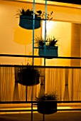 BACK-LIT BALCONY GARDEN AT NIGHT WITH TRANSPARENT PLASTIC RAILINGS AND MINIMAL TRELLIS WITH PLANT HOLDERS.  HEDENS LUSTGARD  SWEDEN.