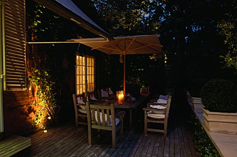 DECKED_TERRACE_WITH_WOODEN_TABLE__CHAIRS_AND_PARASOL__LIT_UP_AT_NIGHT_WITH_CANDLES_AND_LIGHTS_LIGHTI
