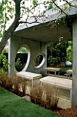 CONCRETE ROOM WITH OVAL WINDOWS  DECKED TERRACE AND CONCRETE AND METAL SEATS. DESIGNER: DIARMUID GAVIN