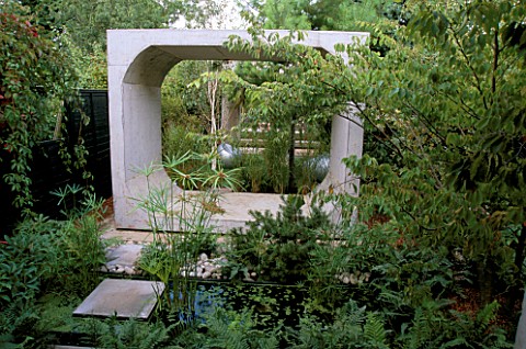 VIEW_DOWN_LONG_THIN_GARDEN_WITH_MASSIVE_CONCRETE_FRAMES__FERNS__WATER_AND_PAPYRUS_DESIGNER_DIARMUID_