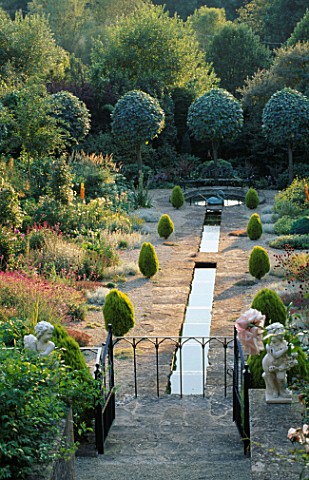 VIEW_FROM_THE_HOUSE_ALONG_THE_RILL_GARDEN_IN_THE_EVENING_WITH_CLIPPED_SHAPES_OF_SORBUS_ARIA_LUTESCEN