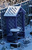 PURPLE COVERED SEAT FLANKED BY METAL URNS AND BACKED BY BLUE DECORATIVE FENCING IN THE NICHOLS GARDEN AT 69  ALBERT ROAD  READING  COVERED WITH SNOW