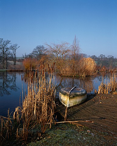 LADY_FARM__SOMERSET__IN_WINTER_THE_LAKE_WITH_ROWING_BOAT_AND_BULLRUSHES