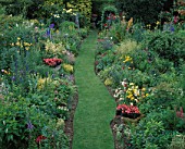 RED GABLES  WORCESTERSHIRE: HERBACEOUS BORDERS AND GRASS WALK WITH URNS PLANTED WITH PELARGONIUM RED GABLES