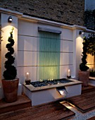 MODERN ROOF GARDEN WITH DECKING  GLASS WATER FEATURE  CLIPPED BOX  RILL  CANDLES. DEVELOPMENT BY CANDY BROTHERS.  LIGHTING BY LIGHTING DESIGN INTERNATIONAL