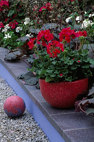 PINKY_RED_CONCRETE_CONTAINER_PLANTED_WITH_PELARGONIUMS__WITH_RED_CONCRETE_SPHERE__DESIGNER_CAROLE_VI
