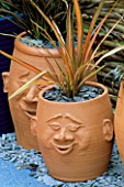 TERRACOTTA POTS WITH FACES PLANTED WITH PHORMIUMS
