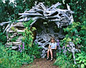 HAZEL SITS IN THE STUMPERY CAVE MADE FROM CANADIAN DRIFTWOOD  DESIGNED BY PHILIP GAME FOR MARNEY HALL