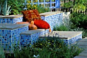 CONCRETE SEATS COVERED WITH MOSAICS AND RED CUSHIONS AT THE HAMPTON COURT FLOWER SHOW 2001. DESIGNER ELIZABETH APEDAILE/DOVE LANDSCAPES