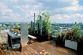 AFRICAN THEMED ROOF TERRACE: VIEW OVER LONDON. WATER FEATURE IN BLACK POWDER-COATED CONTAINER  FIVE LEAD SCULPTURES BY SHAUN BROSNAN.  IROKO DECKING.  DESIGN: S. WOODHAMS