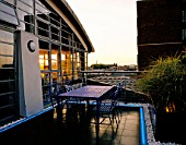ROOF GARDEN DESIGNED BY STEPHEN WOODHAMS: BLACK SLATE TERRACE WITH TABLE AND CHAIRS AND NEON STRIP LIGHTING