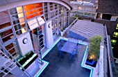 ROOF GARDEN DESIGNED BY STEPHEN WOODHAMS LIT UP AT NIGHT: BLACK SLATE TERRACE WITH TABLE AND CHAIRS AND NEON STRIP LIGHTING ON THE FIFTH FLOOR
