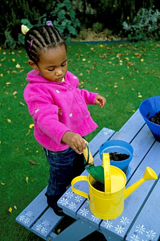 ANNA_NYUN_FORBANG_PLANTING_BEANS_WITH_YELLOW_WATERING_CAN_BESIDE_HER