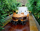 ROOF TERRACE WITH DECKING AT NIGHT:  WOODEN TABLE AND CHAIRS  GALVANISED METAL CONTAINERS WITH BAMBOO  WHITEWASHED WALL :DESIGNED BY WYNNIATT-HUSEY CLARKE