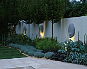 THE SANCTUARY GARDEN  CHELSEA 2002  LIT UP AT NIGHT. DESIGNER: STEPHEN WOODHAMS:WALL WITH  5 FACE SCULPTURE BY STEPHEN COX