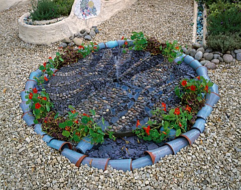 SPANISH_STYLE_GARDEN_WITH_GRAVEL__WATER_FEATURE_MADE_FROM_PEBBLES_NASTURTIUMS__MOSAICS_THE_GAUDI_GAR