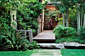VIEW ALONG FRONT WOODEN PATH WITH LAWN  STONE WATER FEATURE WITH COPPER PIPE  ROCK  DECKING AND ASPENS. DESIGNER BOB SWAIN  SEATTLE  USA