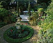 SMALL GARDEN DESIGNED BY LISETTE PLEASANCE: GRAVEL  CIRCLE OF LAWN  HARD ITALIAN LIMESTONE FLOOR  TULIPS AND TERRACOTTA POTS PLANTED WITH BOX BALLS