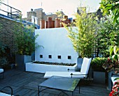 ROOF GARDEN WITH DECKING  WHITE WATER FEATURE  CHAIRS AND GALVANISED POTS PLANTED WITH BAMBOOS. DESIGNERS: PATRICK WYNNIAT - HUSEY AND PATRICK CLARKE