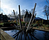 BURY COURT  SURREY  IN AUTUMN: RECTANGULAR POND AND SCULPTURE BY PAUL ANDERSON WITH THE OAST HOUSES BEHIND.