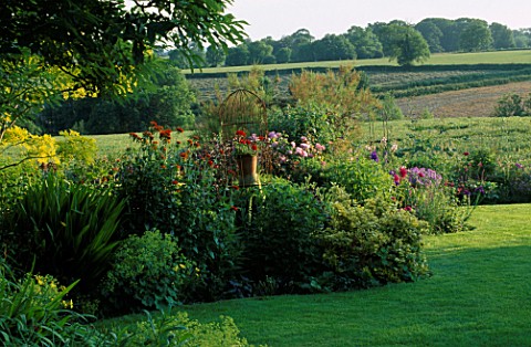 LAUNA_SLATTERS_GARDEN_OXFORDSHIRE_LAWN_AND_BORDER_WITH_COUNTRYSIDE_BEYOND