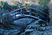 FROSTED BLUE WOODEN BRIDGE OVER A SMALL STREAM  AT THE LANCE HATTATT DESIGN GARDEN AT ARROW COTTAGE  HEREFORDSHIRE