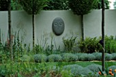 SANCTUARY GARDEN SPONSORED BY MERRILL LYNCH AT THE CHELSEA FLOWER SHOW 2002: DESIGNED BY STEPHEN WOODHAMS: ONE OF THE FIVE FACE SCULPTURES BY STEPHEN COX BESIDE CLIPPED SANTOLINA