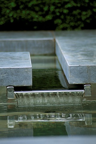 WATER_TRICKLES_OVER_LIP_IN_RAISED__SLATEEDGED_WATER_FEATURE_IN_THE_CANCER_RESEARCHATRIXOS_GARDEN__CH