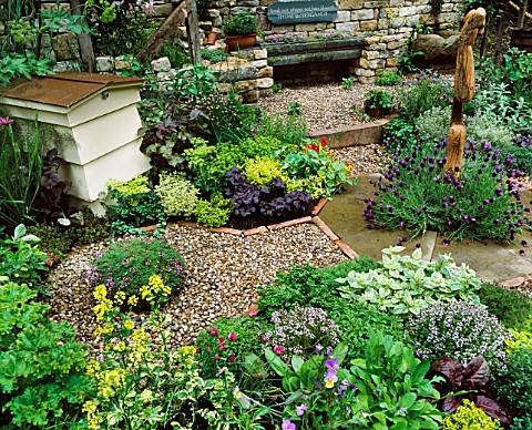 VIEW_ACROSS_HERB_SOCIETYS_GARDEN__CHELSEA_2003_CHIVES_SURROUND_CENTRAL_WOODEN_FEATURE_BY_JON_EDGAR_W
