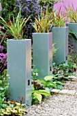 STEEL PLANTERS PLANTED WITH JAPANESE BLOOD GRASS  UNCINIA CYLINDRICA RUBRA. THE CATWALK GARDEN  CHELSEA FLOWER SHOW 2003. DESIGNER: ALAN CAPPER