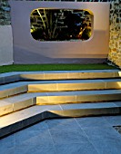 STEPS AND RENDERED CONCRETE APERTURE WITH JELLY PALM (BUTIA CAPITATA) AND SCULPTURE LIT UP AT NIGHT IN SMALL COURTYARD. DESIGNER: AMIR SCHLEZINGER/MY LANDSCAPES