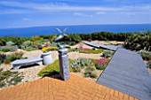 SEASIDE GARDEN  GUERNSEY: VIEW OUT TO SEA WITH BRICK PATIO  GRAVEL  WOODEN BOARDWALK  CHINESE GRANITE SEAT  AND SEAGULLS SCULPTURE BY GUY PORTELLI
