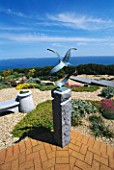 SEASIDE GARDEN  GUERNSEY: VIEW OUT TO SEA WITH BRICK PATIO  GRAVEL  CHINESE GRANITE SEAT  AND SEAGULLS SCULPTURE BY GUY PORTELLI