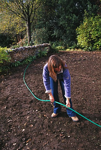 CLARE_MATTHEWS_USING_A_HOSE_TO_LAY_OUT_A_PATH_IN_HER_DEVON_GARDEN