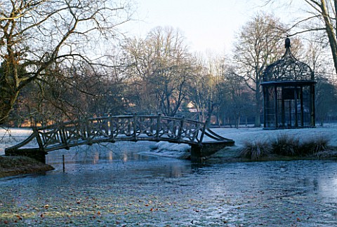 WEST_GREEN_HOUSE_GARDEN__HAMPSHIRE_ORNAMENTAL_BIRD_CAGE_AND_BRIDGE_BESIDE_A_LAKE_IN_THE_NEOCLASSICAL