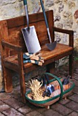 WOODEN BENCH BESIDE WALL WITH TRUG  GLOVES AND SPADE