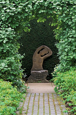 KIFTSGATE_COURT__GLOUCESTERSHIRE_STONE_SEAT_STATUE_BY_SIMON_VERITY_FRAMED_BY_CLIPPED_SORBUS_ARIA_LUT