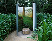 STRAW BALE SEAT SURROUNDED BY CURVED STAINLESS STEEL SCREEN LINED WITH PHOTOGRAPH IN SOMETHINGS WILL NOT GROW GARDEN AT WESTONBIRT2004. DESIGNER: LESLEY KENNEDY