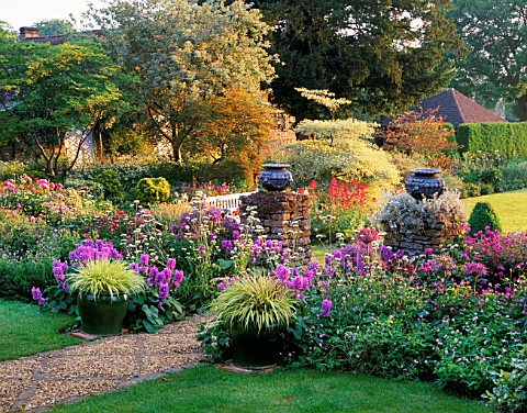 PETTIFERS__OXFORDSHIRE_EARLY_MORNING_LIGHT_ON_EARLY_SUMMER_BORDER_WITH_ALLIUM_CHRISTOPHII__LEAD_URNS