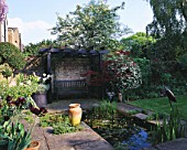 DESIGNER: SHEILA STEDMAN - RECTANGULAR POOL  BLACK TIMBERED ARBOUR AND SEAT  STORK SCULPTURE AND ACER IN A POT