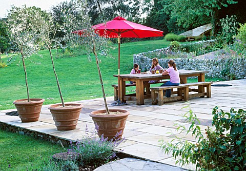 GARDEN_DESIGNER_CLARE_MATTHEWS_RELAXES_WITH_NANCY_AND_HARRIET_AT_A_GREEN_OAK_TABLE_WITH_BENCH_ON_THE