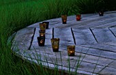 DESIGNER CLARE MATTHEWS: THE DECK CHAIR AT DUSK WITH CANDLES  SURROUNDED BY STIPA ARUNDINACEA